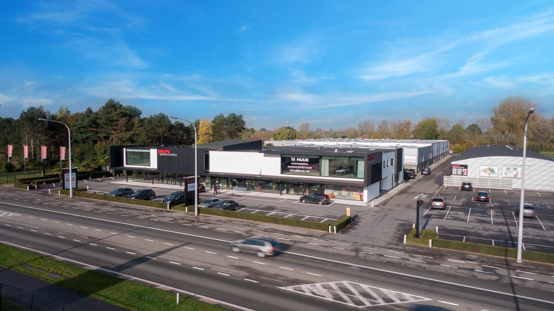 Luchtfoto van de gevel en de parking langs de weg